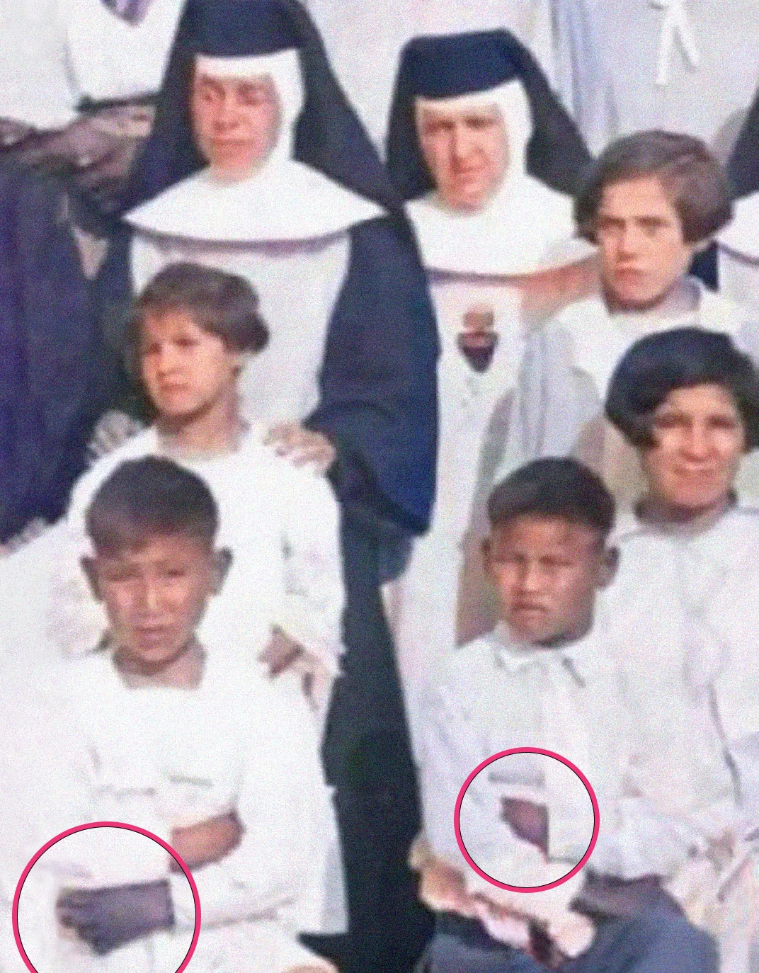 Students posing with nuns have their left hands tied. The hands are visibly purple.