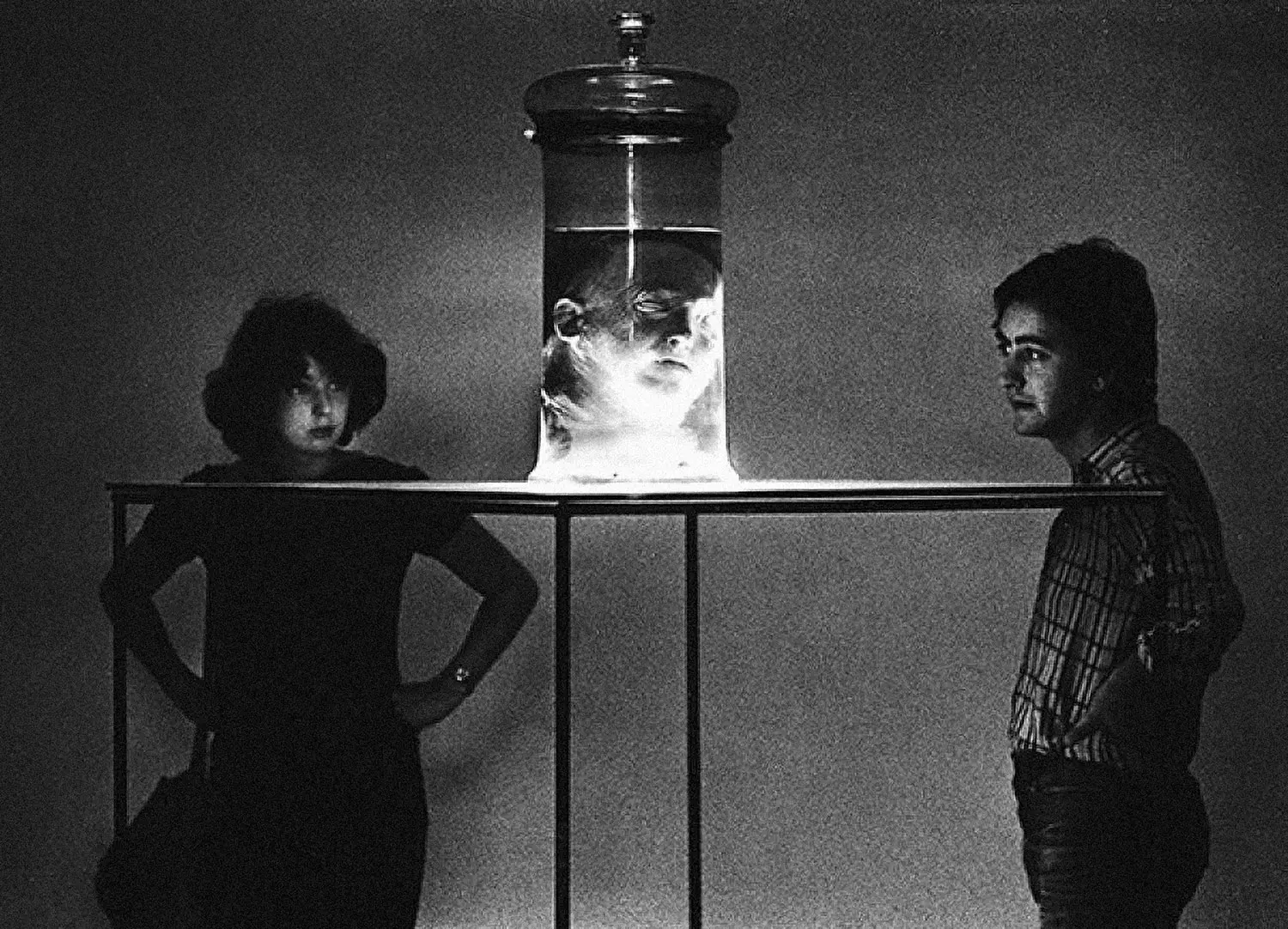 Lombroso’s preserved head is suspended in a jar that’s illuminated from below. A couple inquisitively stares at it. 