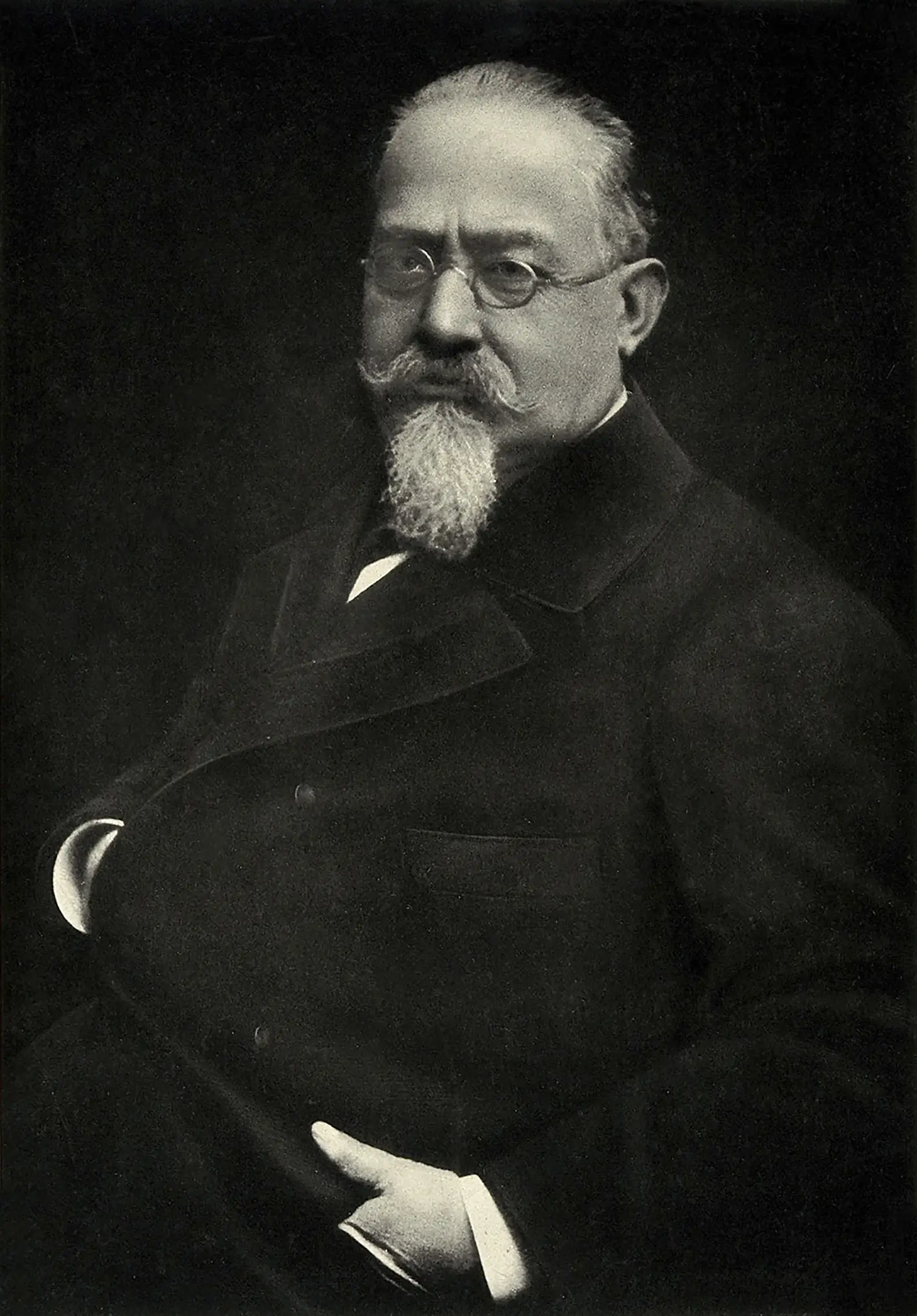 Portrait of Cesare Lombroso sporting glasses, a suit, a long goatee, and mustache.