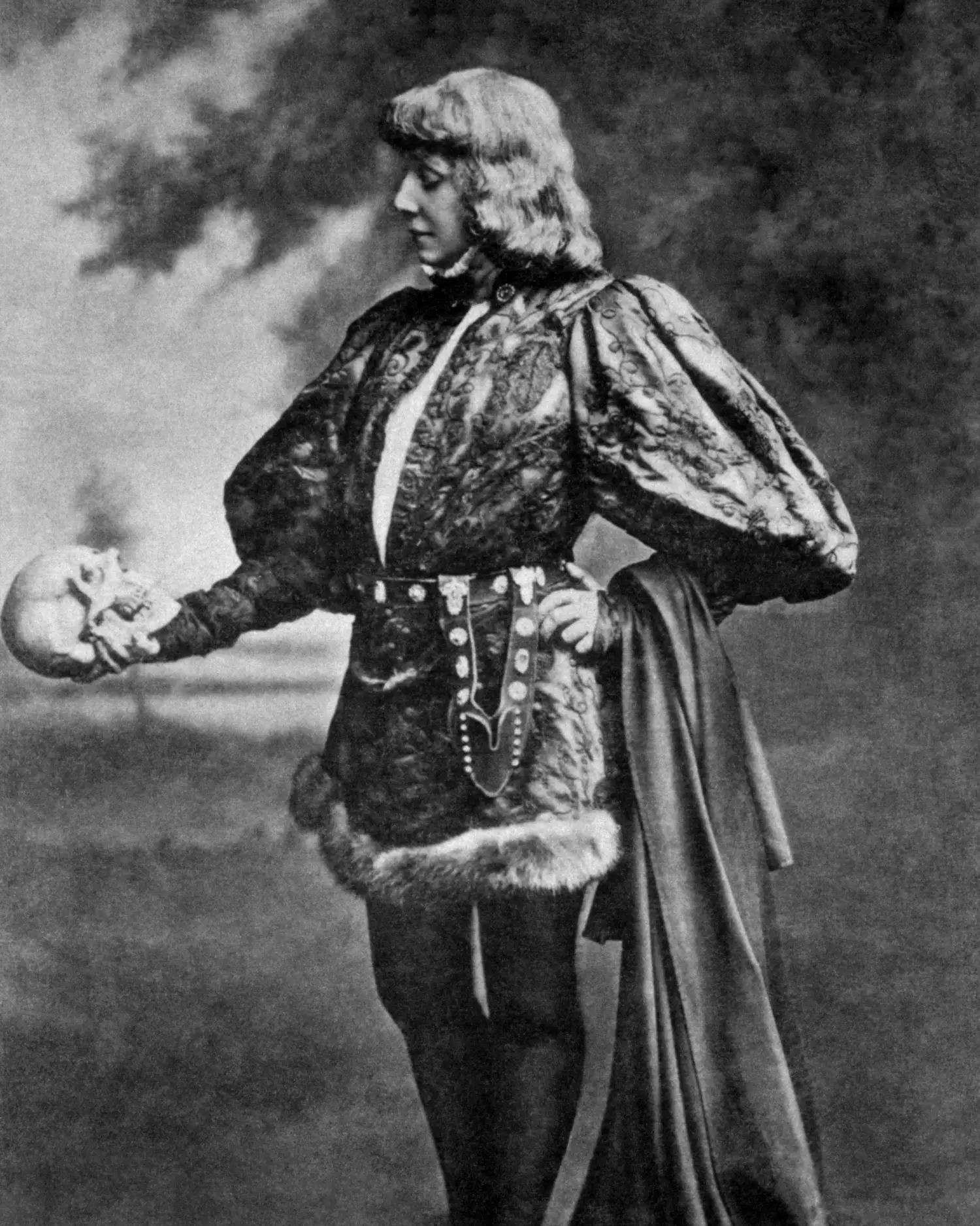 Sarah Bernhardt, donning theatrical attire, stares into Yorick’s skull.