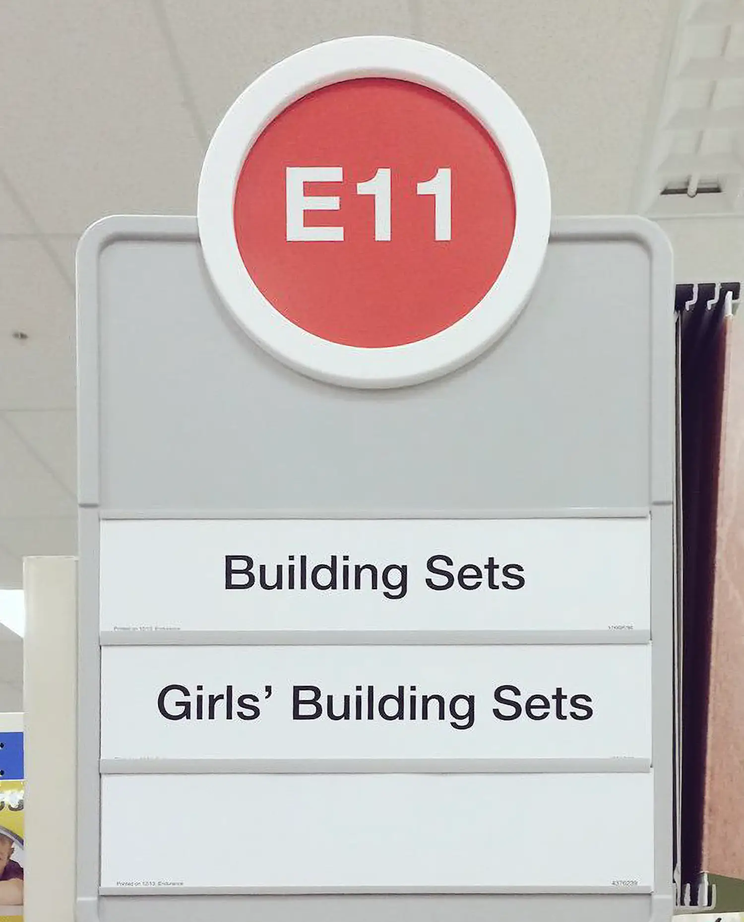 A sign to a supermarket aisle labeled: “Building Sets” and “Girls’ Building Sets.”
