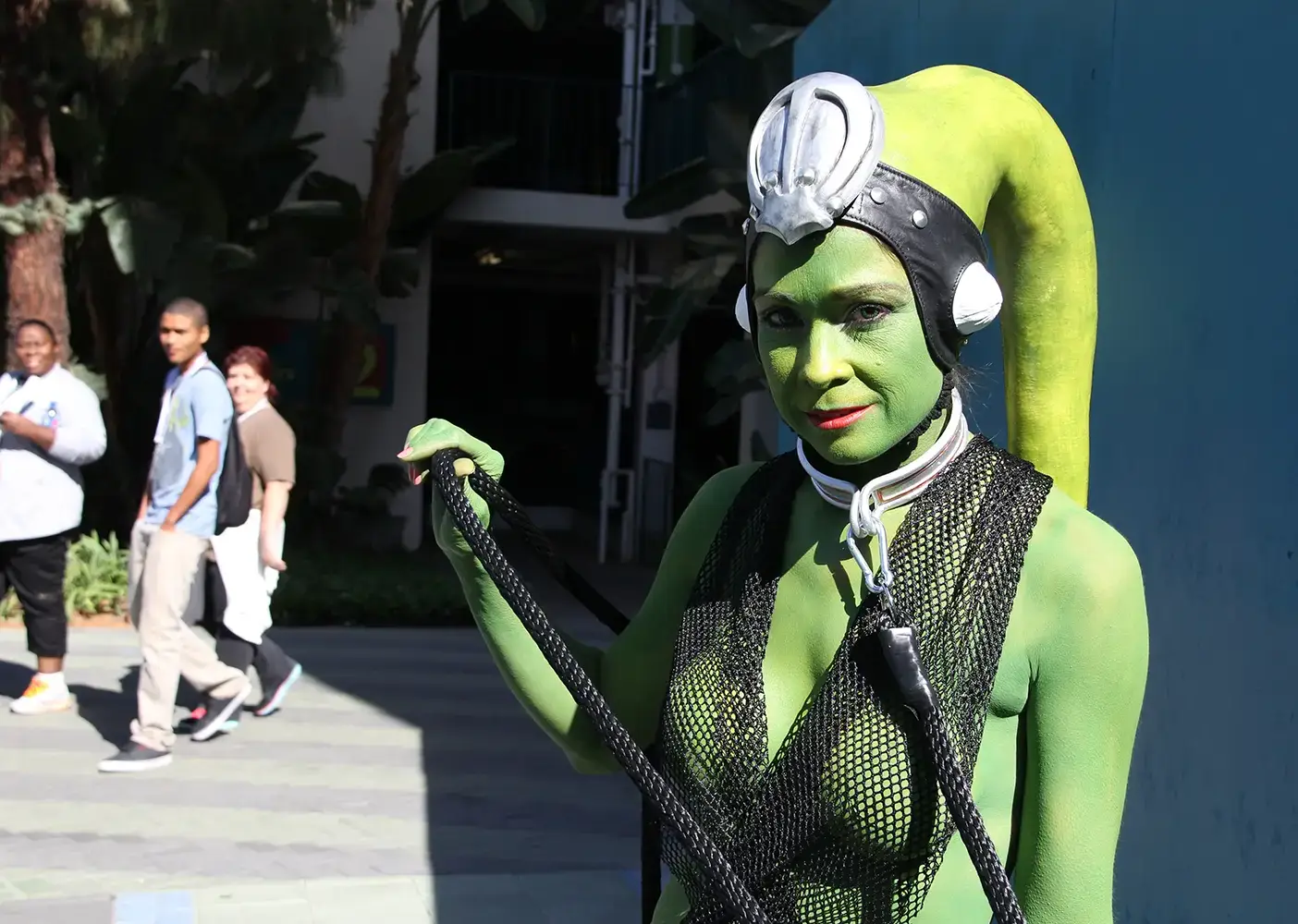 A women whose skin is painted green, wearing green prosthetics, a mesh dress, and a collar, leading her to look like the the Star Wars character Oola.