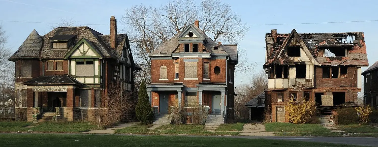 Three large family homes in varying states of decay.