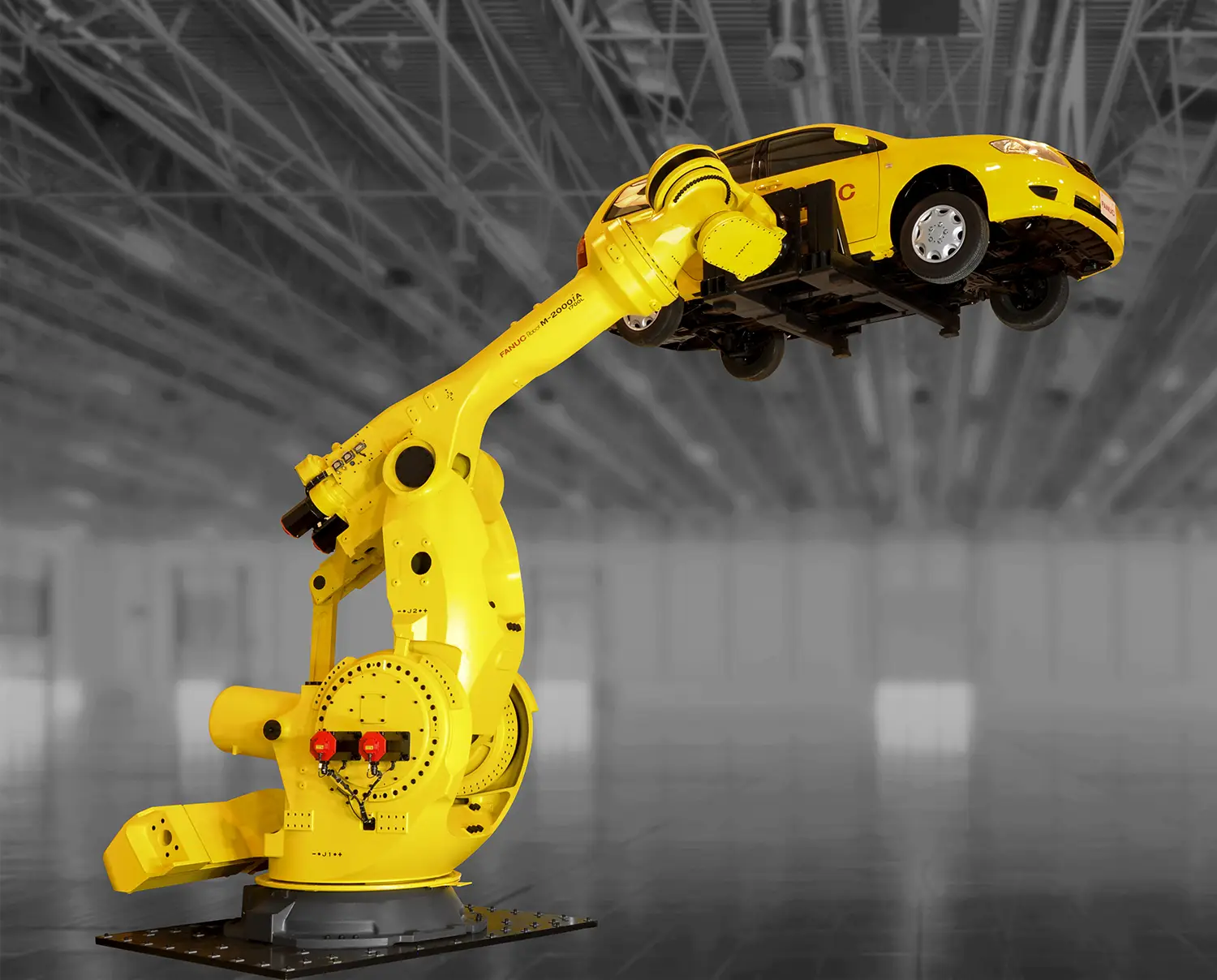 A massive yellow robotic arm lifts a car into the air.