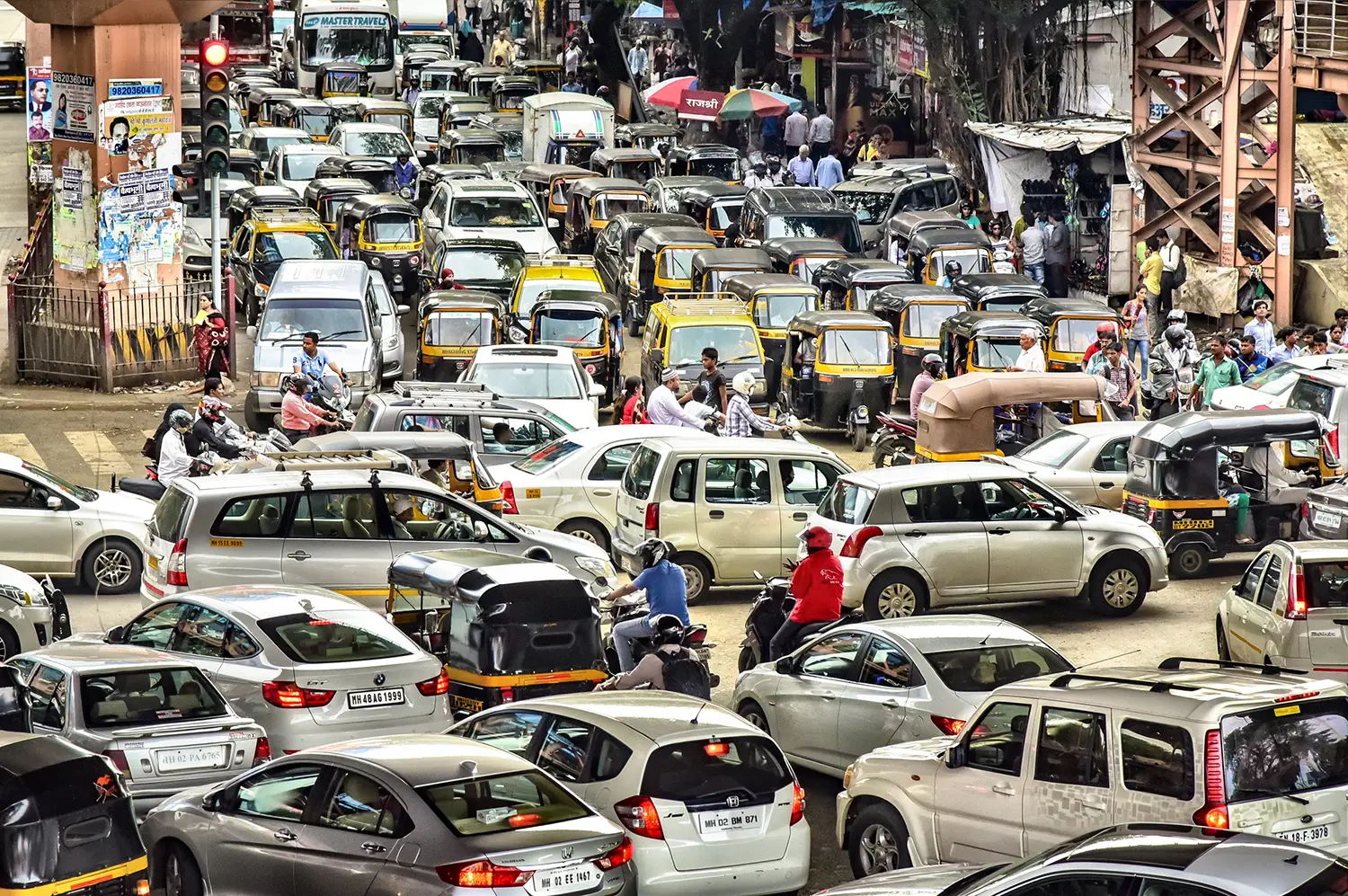 Gridlocked traffic consisting of cars, scooters, rickshaws, buses, and pedestrians.